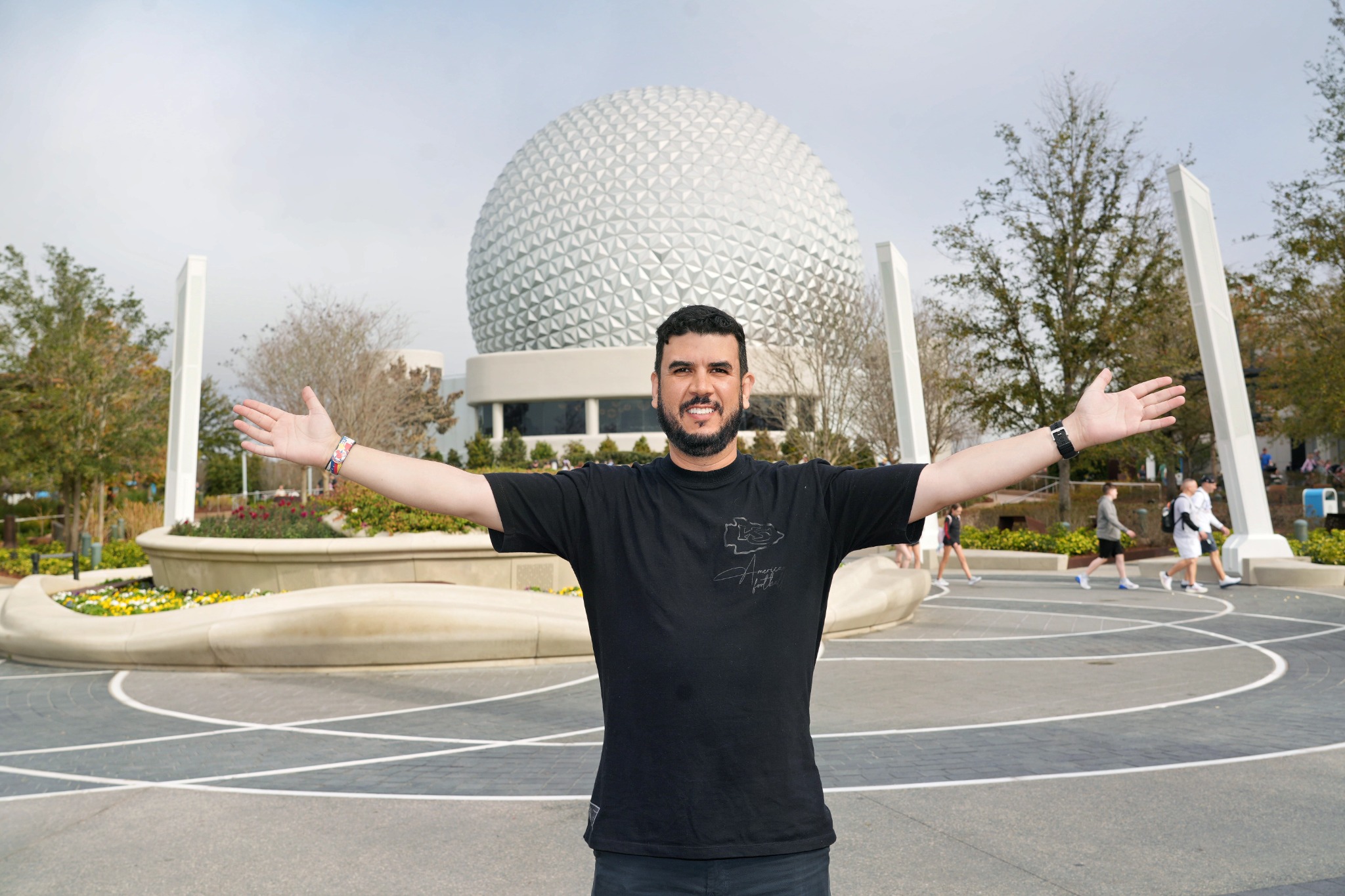 Visitante posa em frente à Spaceship Earth durante um dia ensolarado no EPCOT.