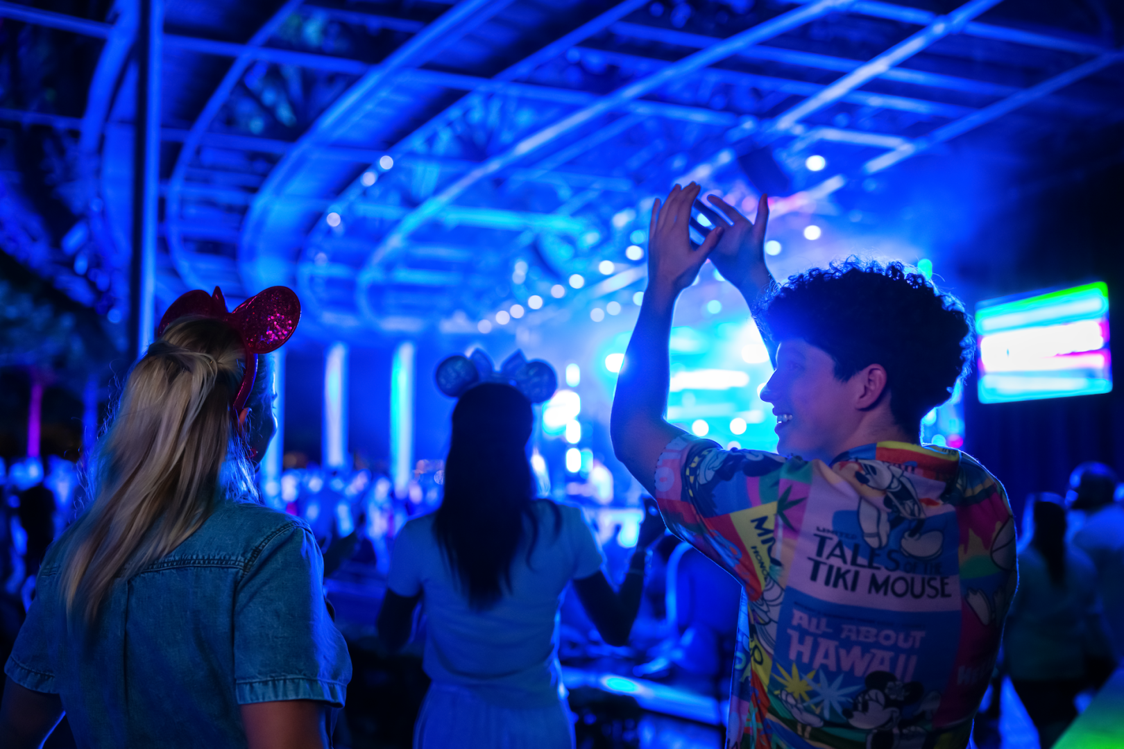 Visitantes acompanham um show noturno do Eat to the Beat diante do palco iluminado no EPCOT.