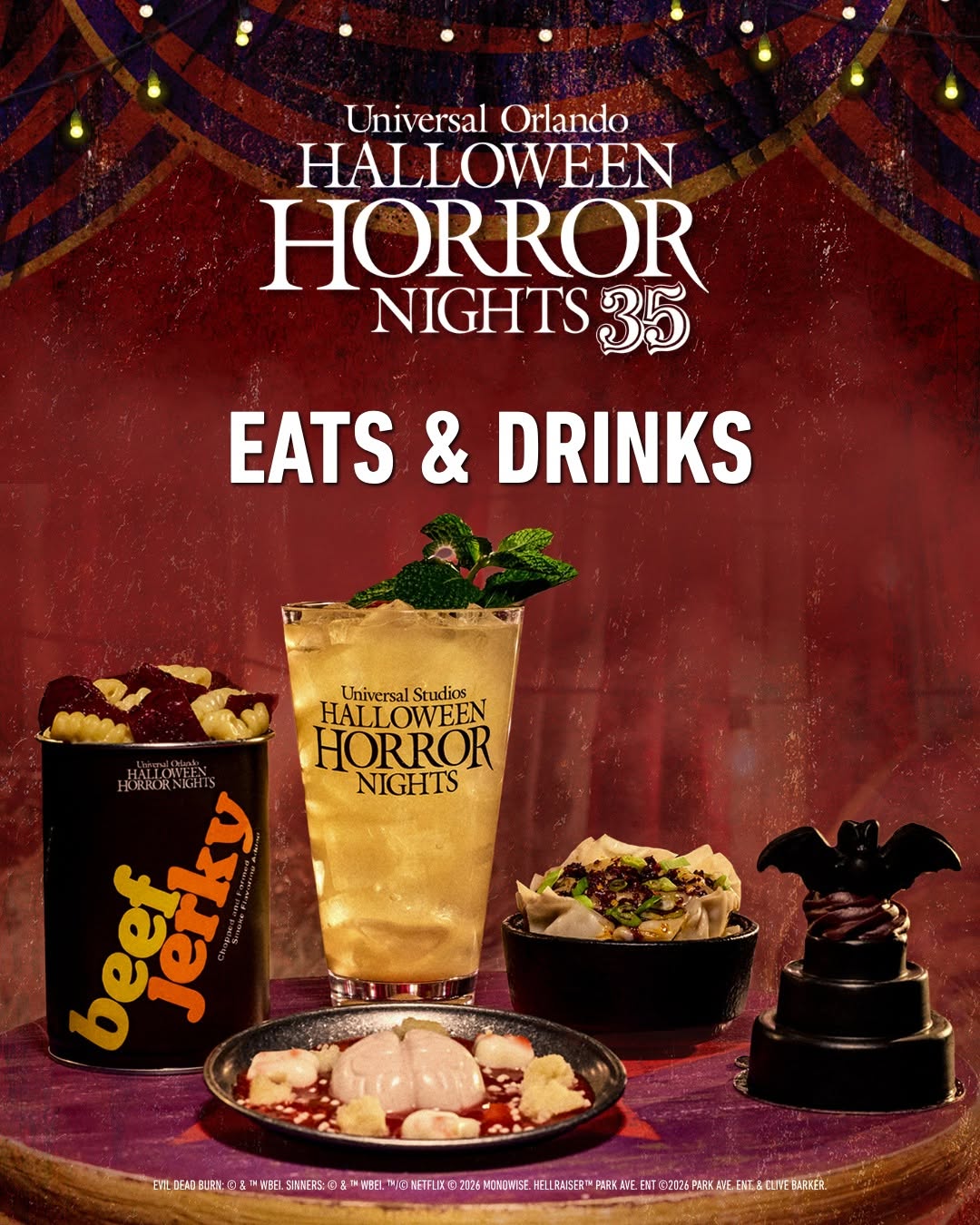 Pratos e bebidas temáticos do Halloween Horror Nights 35 aparecem diante de uma cortina vermelha de circo.