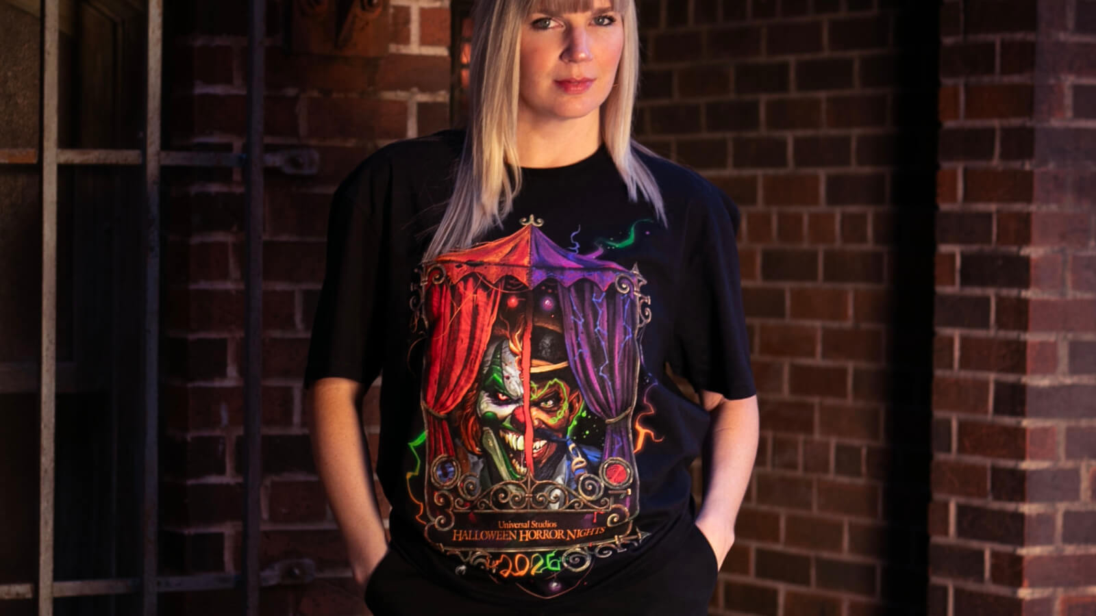 Visitante usa uma camiseta oficial do Halloween Horror Nights 35 diante da entrada do Universal Studios Florida.
