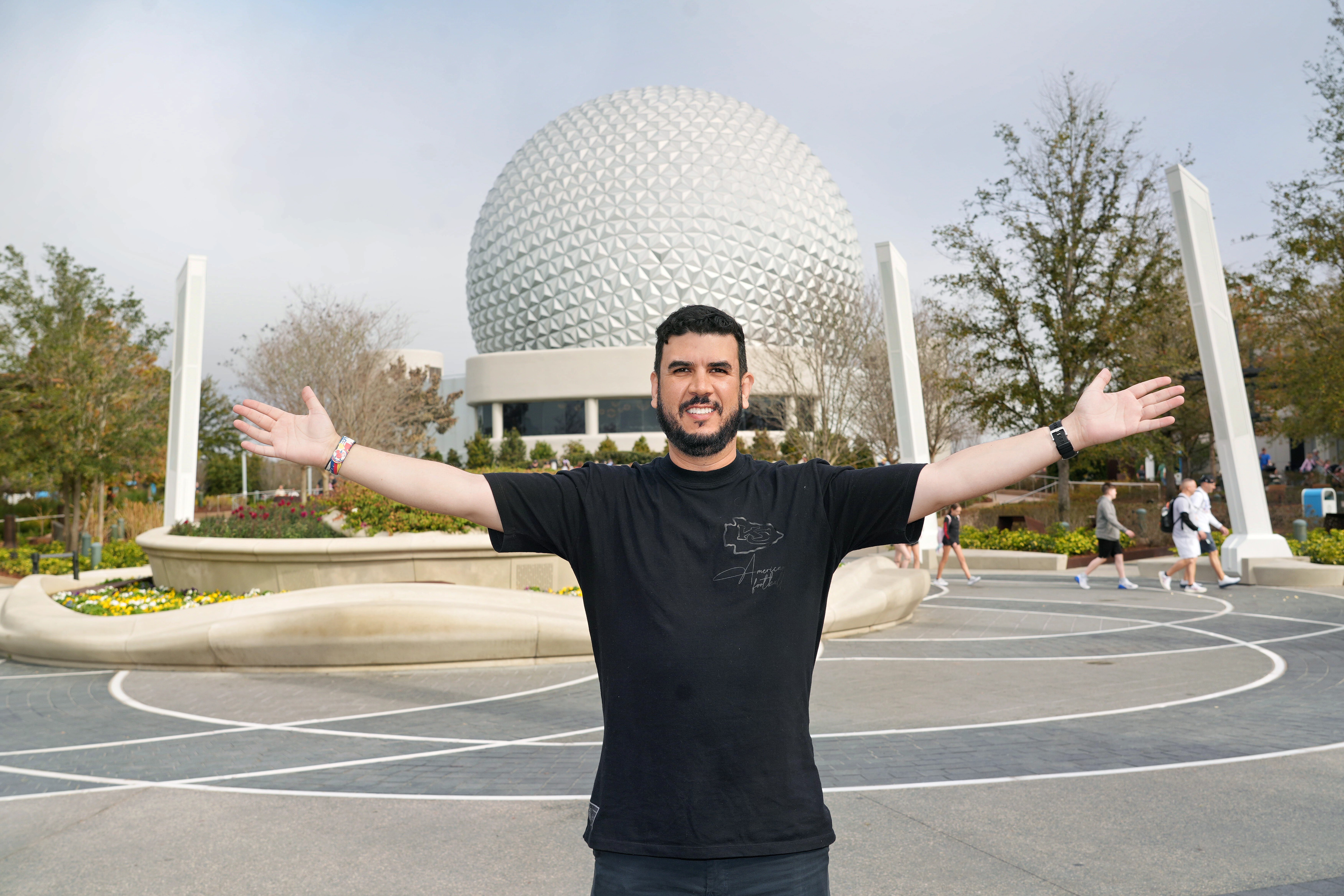 Rodrigo Cabrero abre os braços diante da Spaceship Earth no EPCOT, em Orlando.