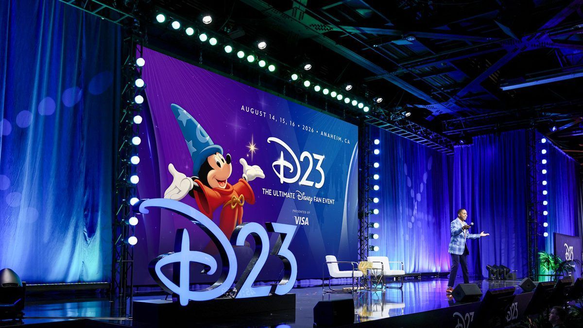Palco do D23: The Ultimate Disney Fan Event, com o Feiticeiro Mickey no telão e a logo D23